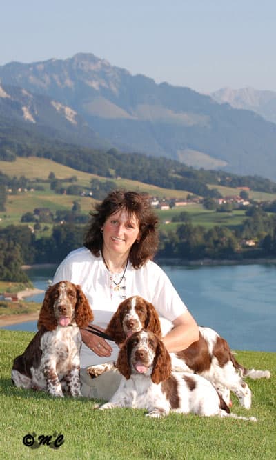 Catherine entourée de ses trois springers spaniels anglais, face au lac et aux Préalpes